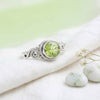[KI] Silberring mit Peridot auf hellem Stoff