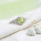 [KI] Silberring mit Peridot auf hellem Stoff