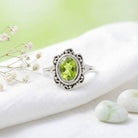 [KI] Silberring mit Peridot auf hellem Stoff