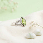 [KI] Silberring mit Peridot auf hellem Stoff