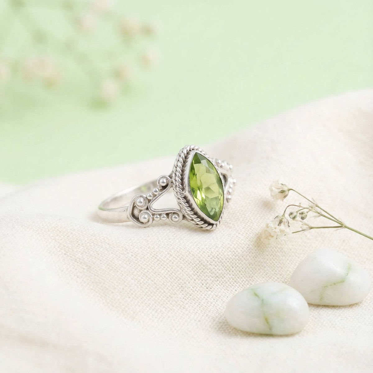 Silberring mit Peridot auf hellem Stoff
