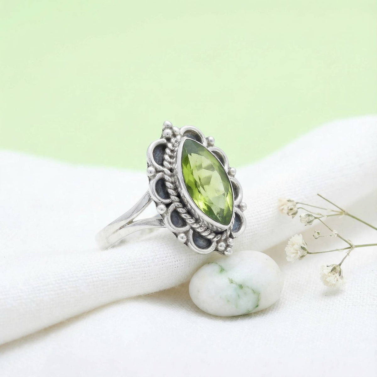 Silberring mit Peridot auf hellem Stoff
