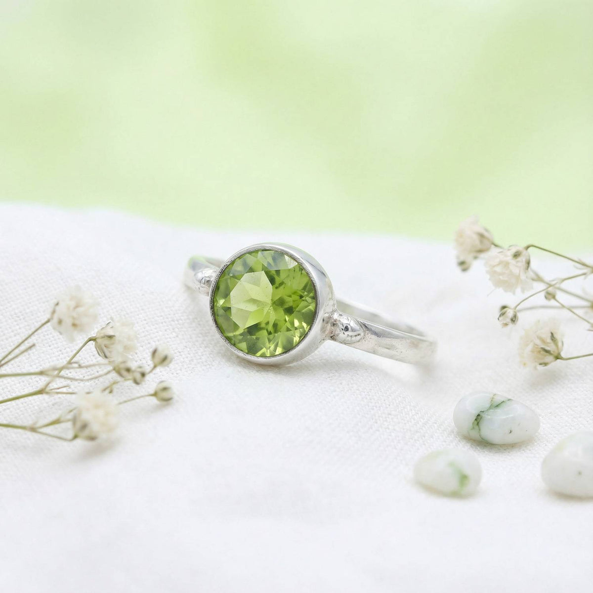 Silberring mit Peridot auf hellem Stoff