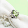 [KI] Silberring mit Peridot auf hellem Stoff