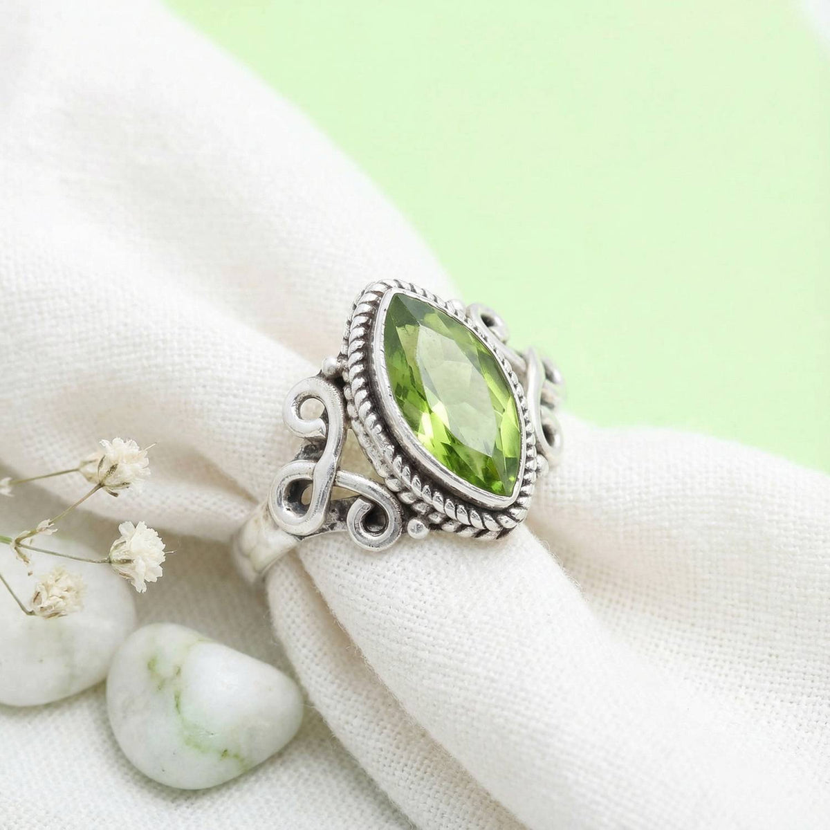 Silberring mit Peridot auf hellem Stoff