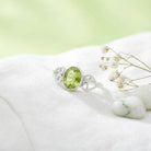 [KI] Silberring mit Peridot auf hellem Stoff