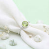 [KI] Silberring mit Peridot auf hellem Stoff