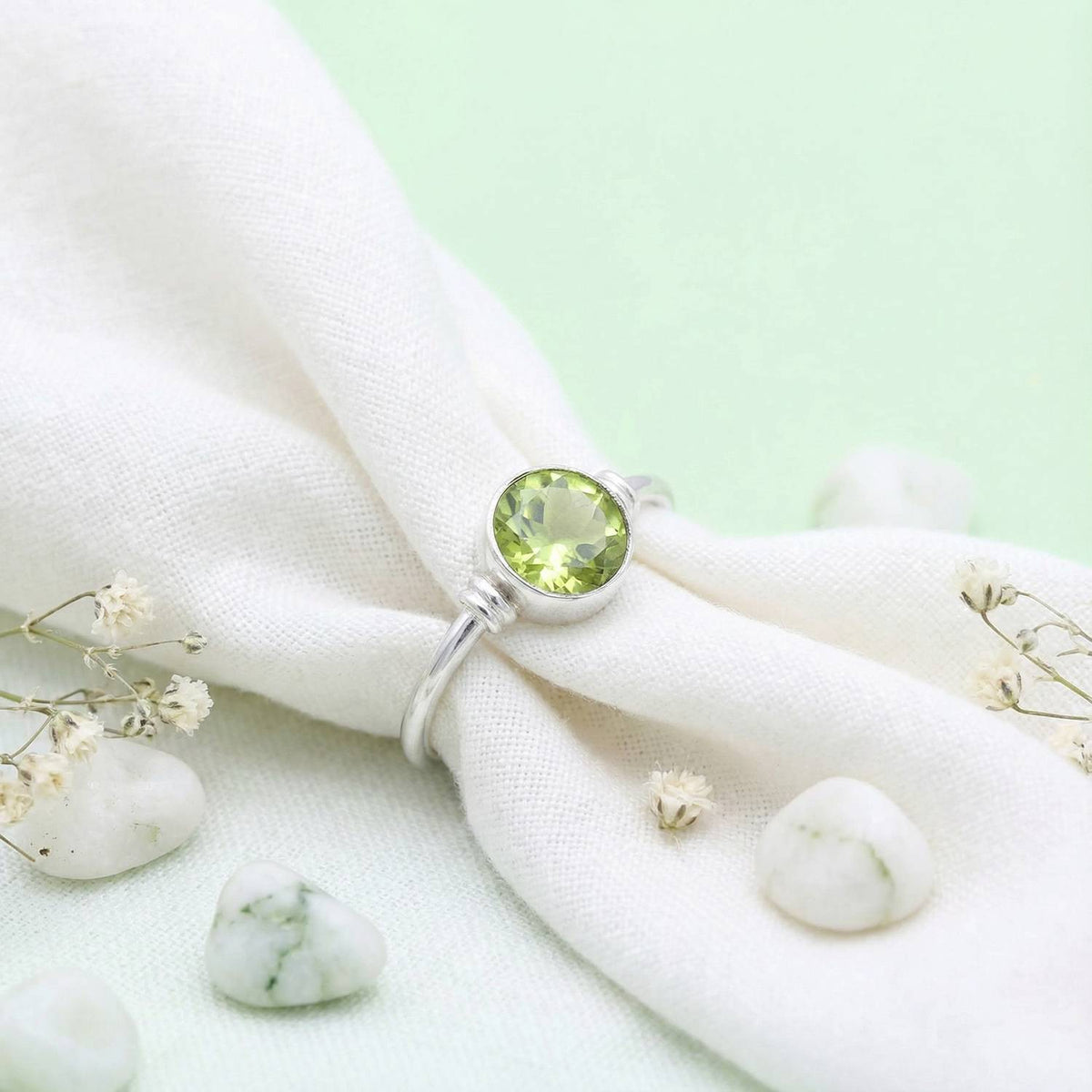 Silberring mit Peridot auf hellem Stoff