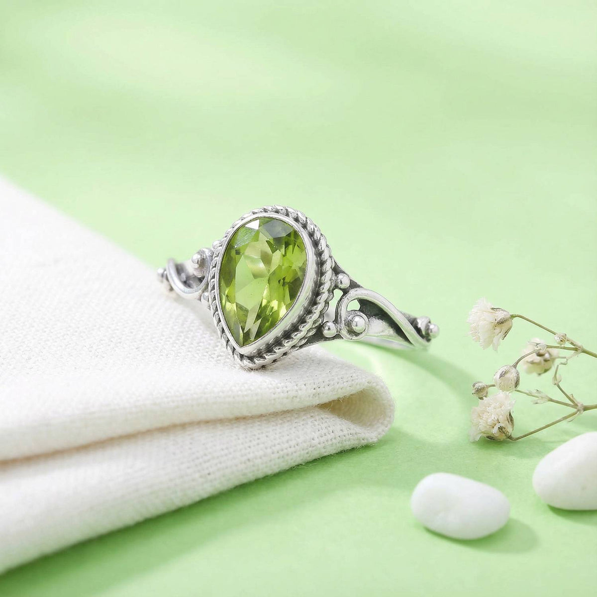 Silberring mit Peridot auf hellem Stoff