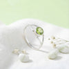 [KI] Silberring mit Peridot auf hellem Stoff