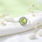 [KI] Silberring mit Peridot auf hellem Stoff
