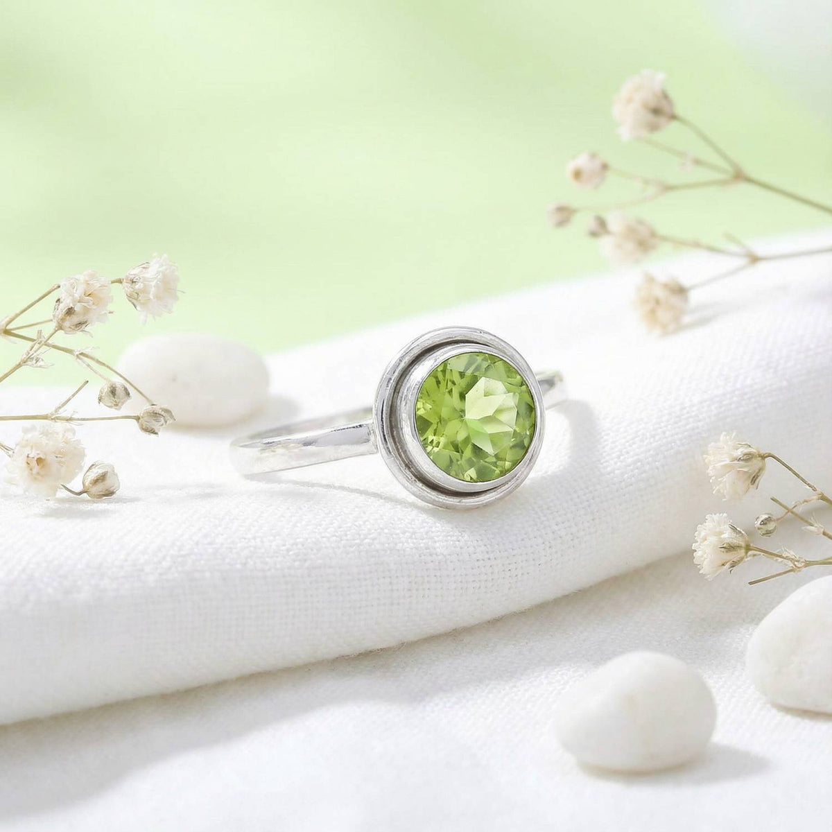 Silberring mit Peridot auf hellem Stoff