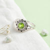 [KI] Silberring mit Peridot auf hellem Stoff