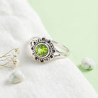 [KI] Silberring mit Peridot auf hellem Stoff