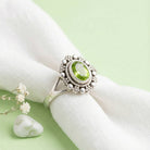 [KI] Silberring mit Peridot auf hellem Stoff