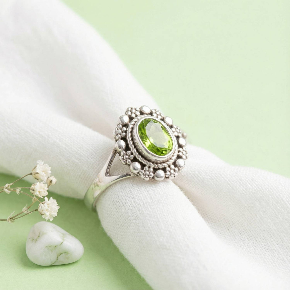Silberring mit Peridot auf hellem Stoff