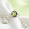 [KI] Silberring mit Peridot auf hellem Stoff