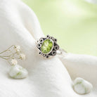 [KI] Silberring mit Peridot auf hellem Stoff