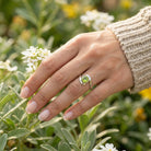 [KI] Silberring mit Peridot an der Hand zwischen Blumen