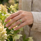 [KI] Silberring mit Peridot an der Hand zwischen Blumen