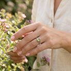 [KI] Silberring mit Peridot an der Hand zwischen Blumen