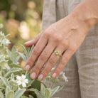 [KI] Silberring mit Peridot an der Hand zwischen Blumen