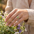 [KI] Silberring mit Peridot an der Hand zwischen Blumen