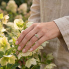 [KI] Silberring mit Peridot an der Hand zwischen Blumen