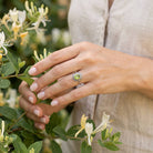 [KI] Silberring mit Peridot an der Hand zwischen Blumen