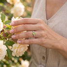 [KI] Silberring mit Peridot an der Hand zwischen Blumen