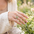 [KI] Silberring mit Peridot an der Hand zwischen Blumen