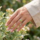 [KI] Silberring mit Peridot an der Hand zwischen Blumen