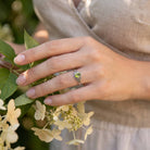 [KI] Silberring mit Peridot an der Hand zwischen Blumen