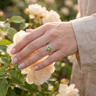 [KI] Silberring mit Peridot an der Hand zwischen Blumen