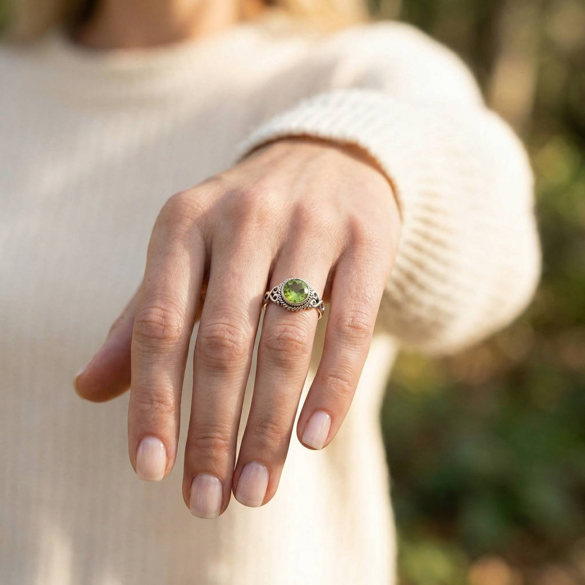 Peridotring aus Silber getragen an der Hand im Freien