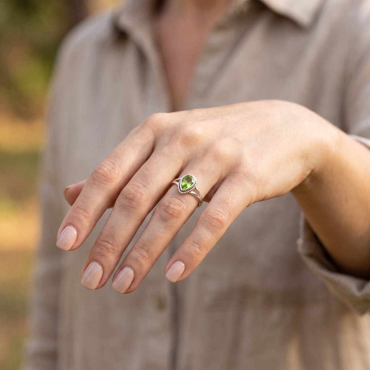 Peridotring aus Silber getragen an der Hand im Freien