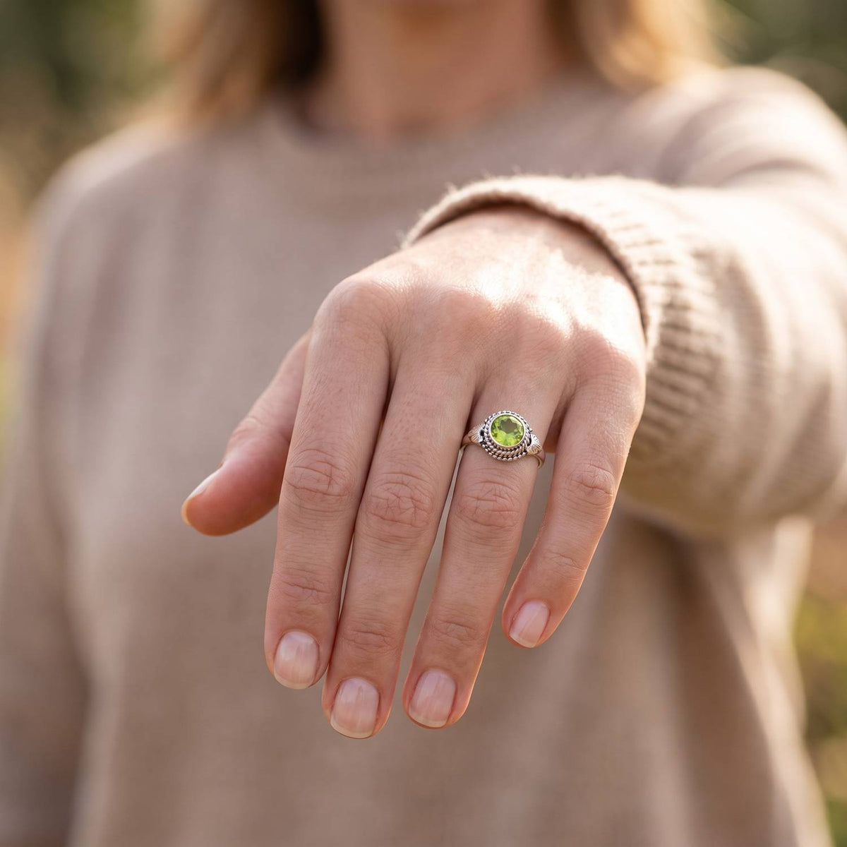 Peridotring aus Silber getragen an der Hand im Freien