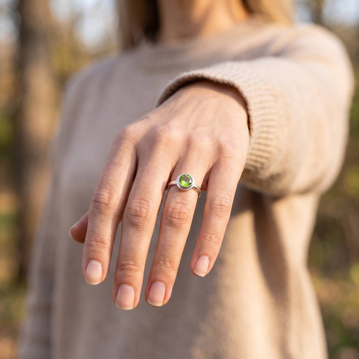 Peridotring aus Silber getragen an der Hand im Freien