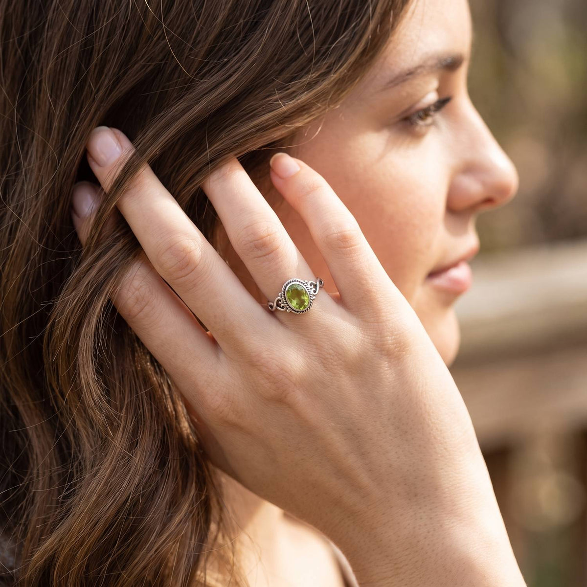 Frau trägt Silberring mit Peridot an der Hand am Haar