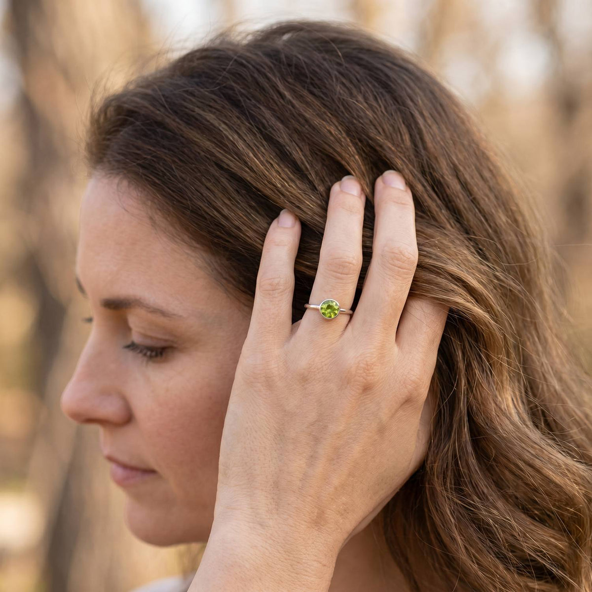 Frau trägt Silberring mit Peridot an der Hand am Haar
