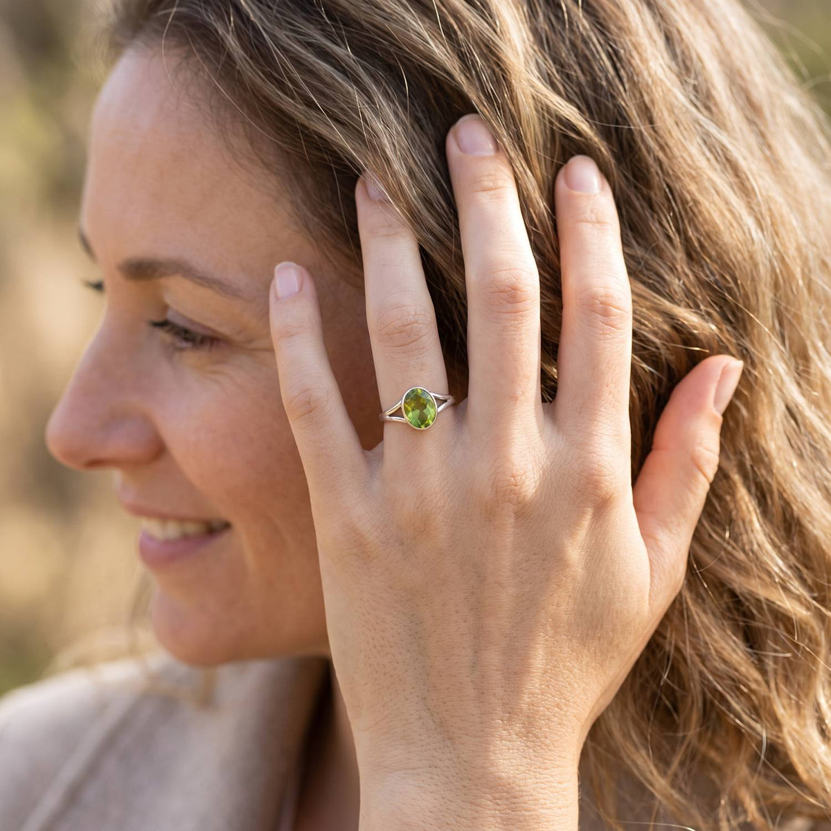 Frau trägt Silberring mit Peridot an der Hand am Haar