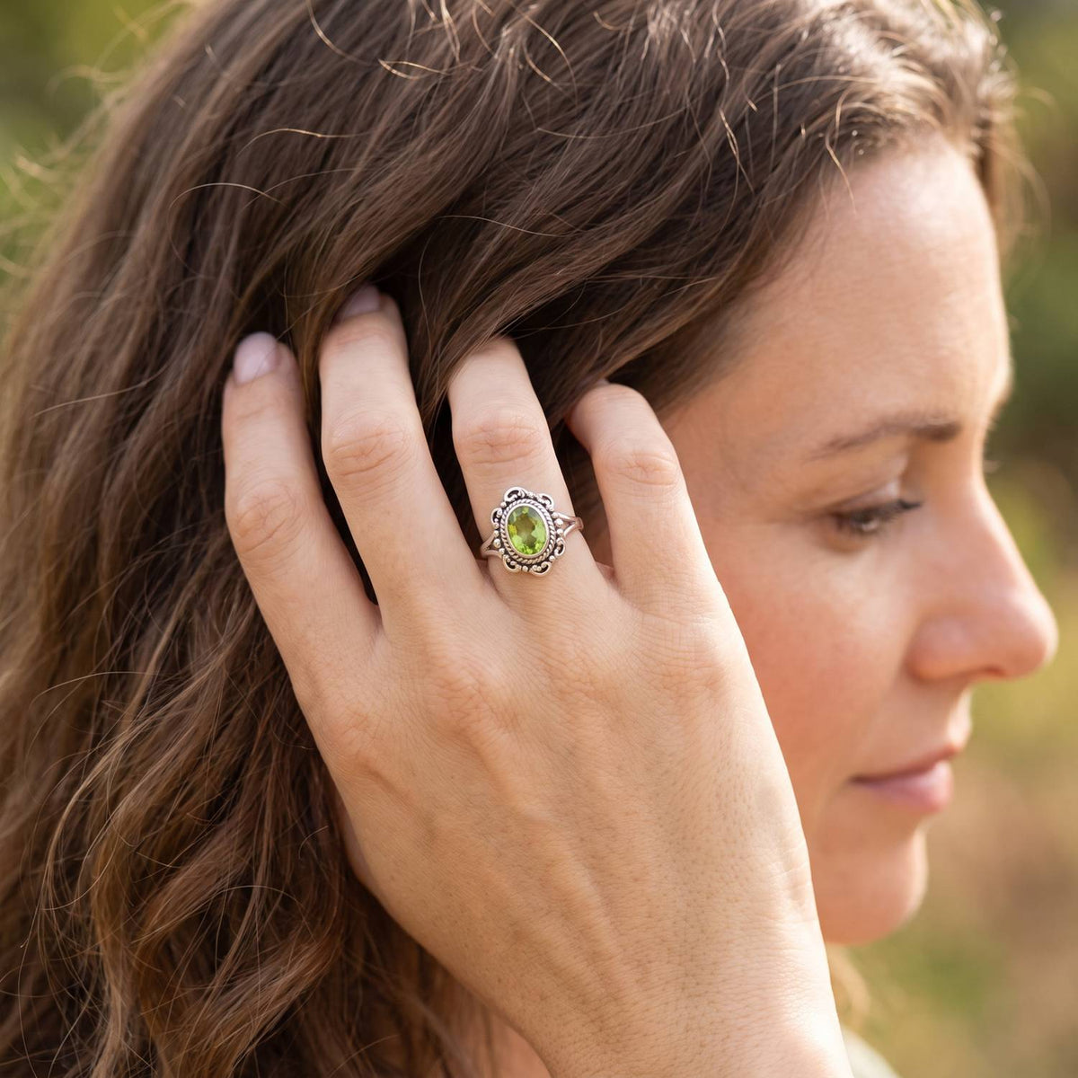 Frau trägt Silberring mit Peridot an der Hand am Haar
