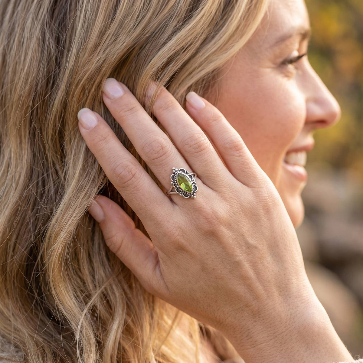 Frau trägt Silberring mit Peridot an der Hand am Haar