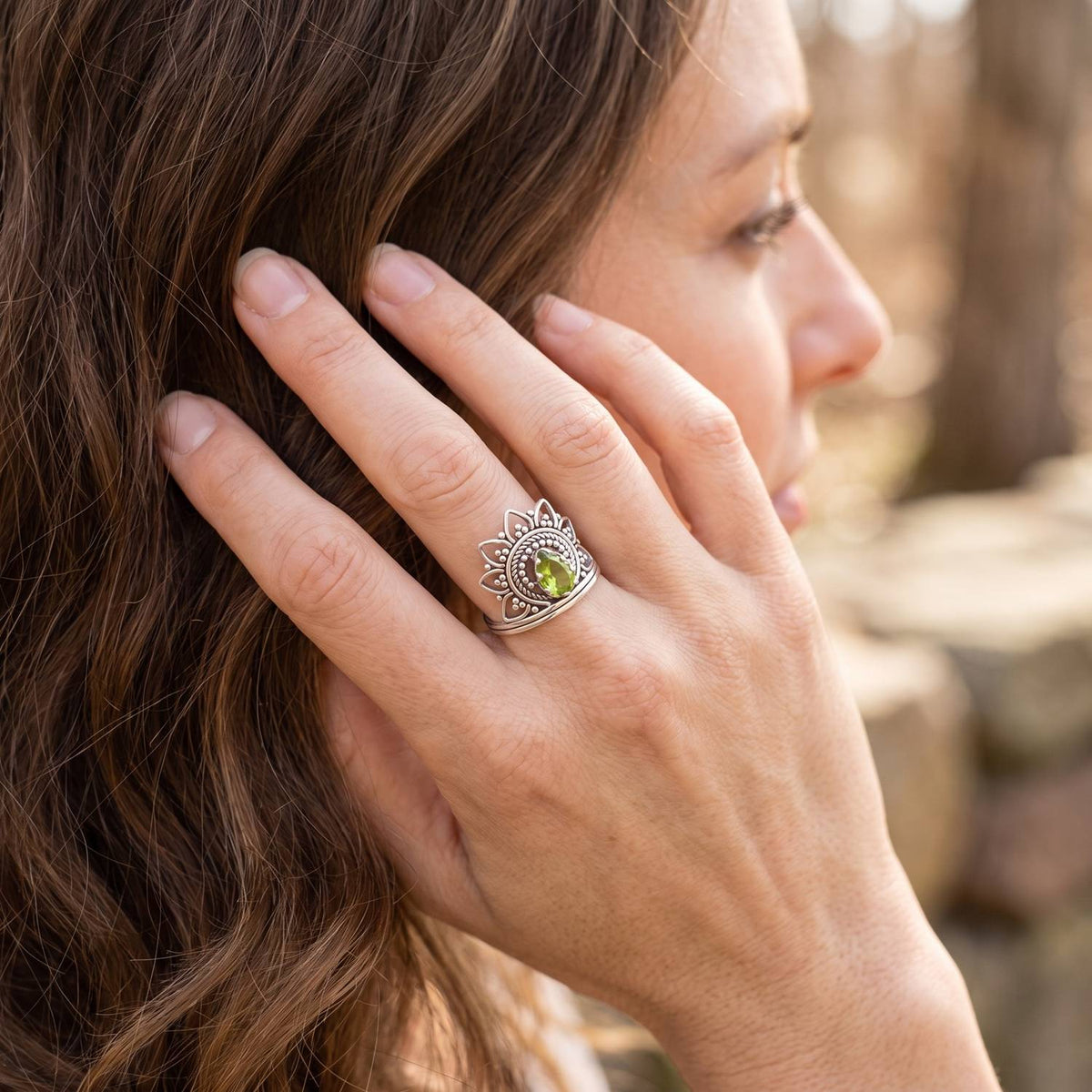 Frau trägt Silberring mit Peridot an der Hand am Haar