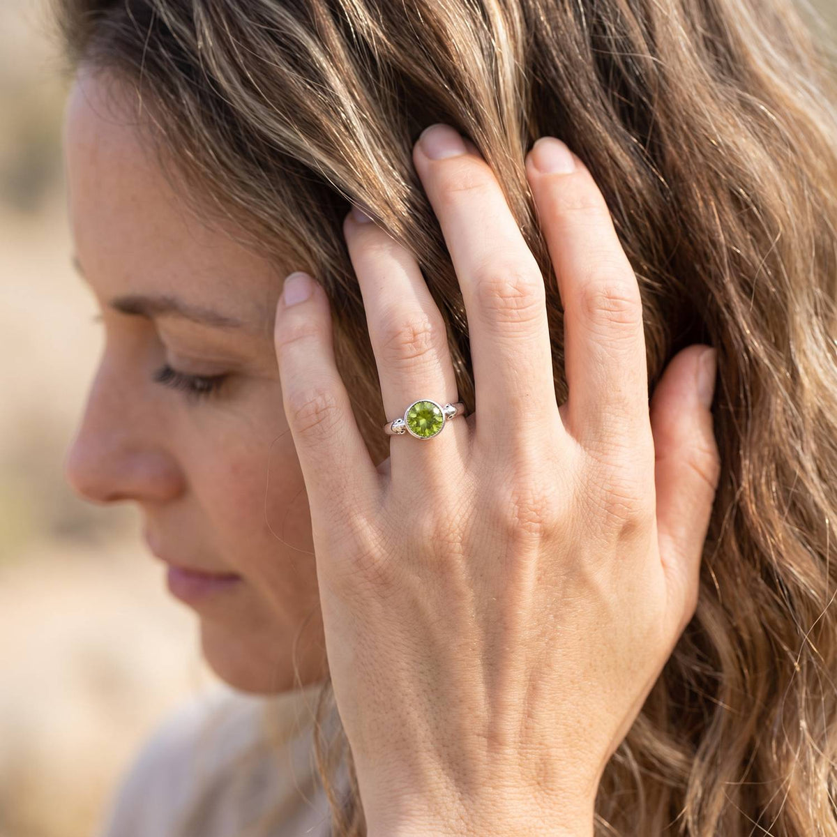 Frau trägt Silberring mit Peridot an der Hand am Haar