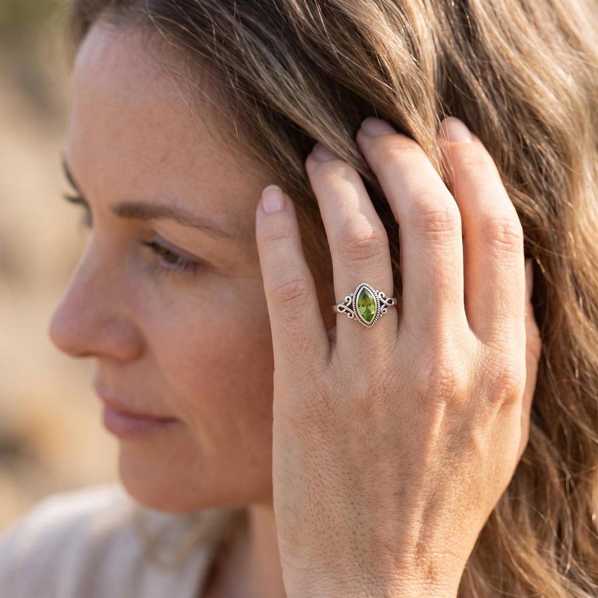 Frau trägt Silberring mit Peridot an der Hand am Haar