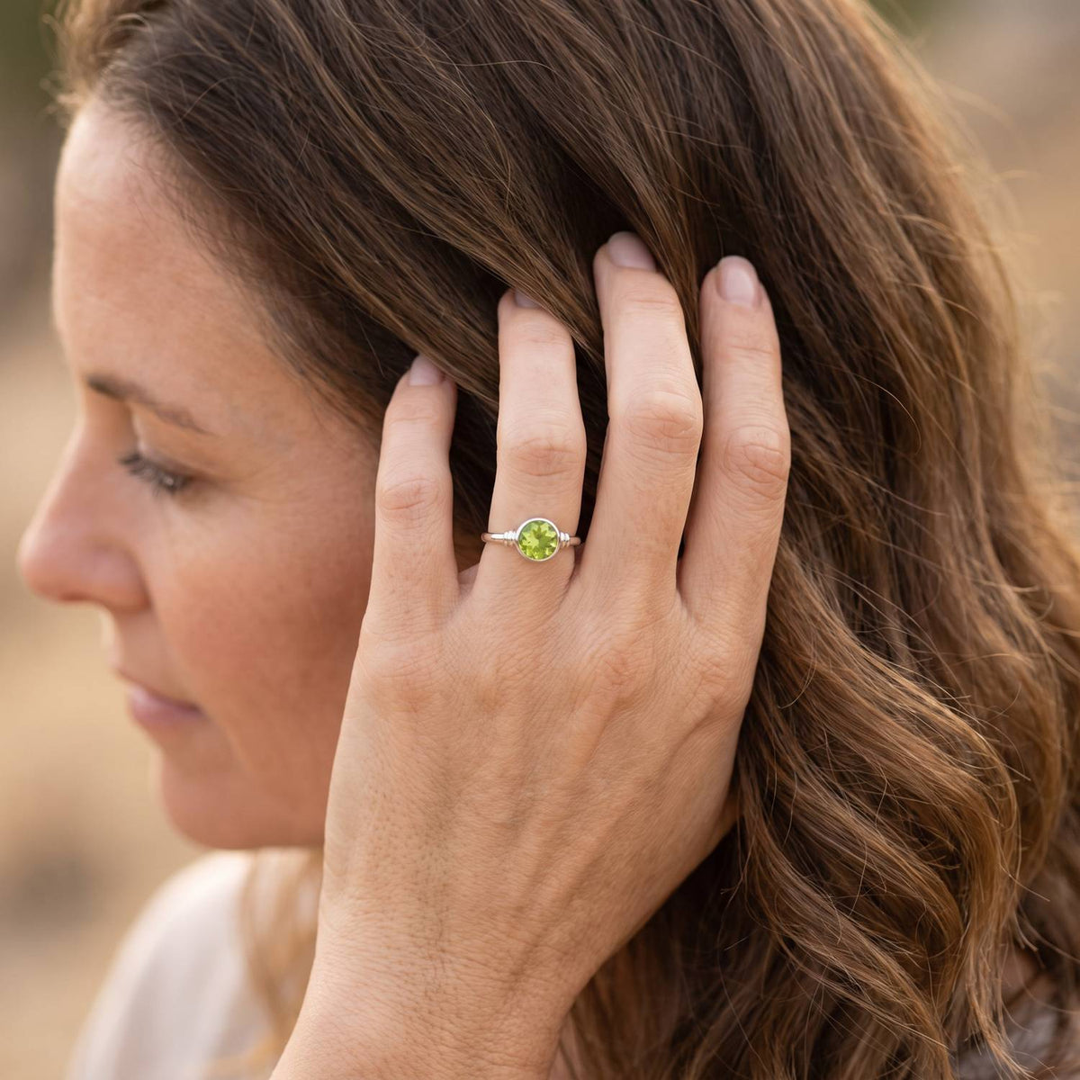 Frau trägt Silberring mit Peridot an der Hand am Haar