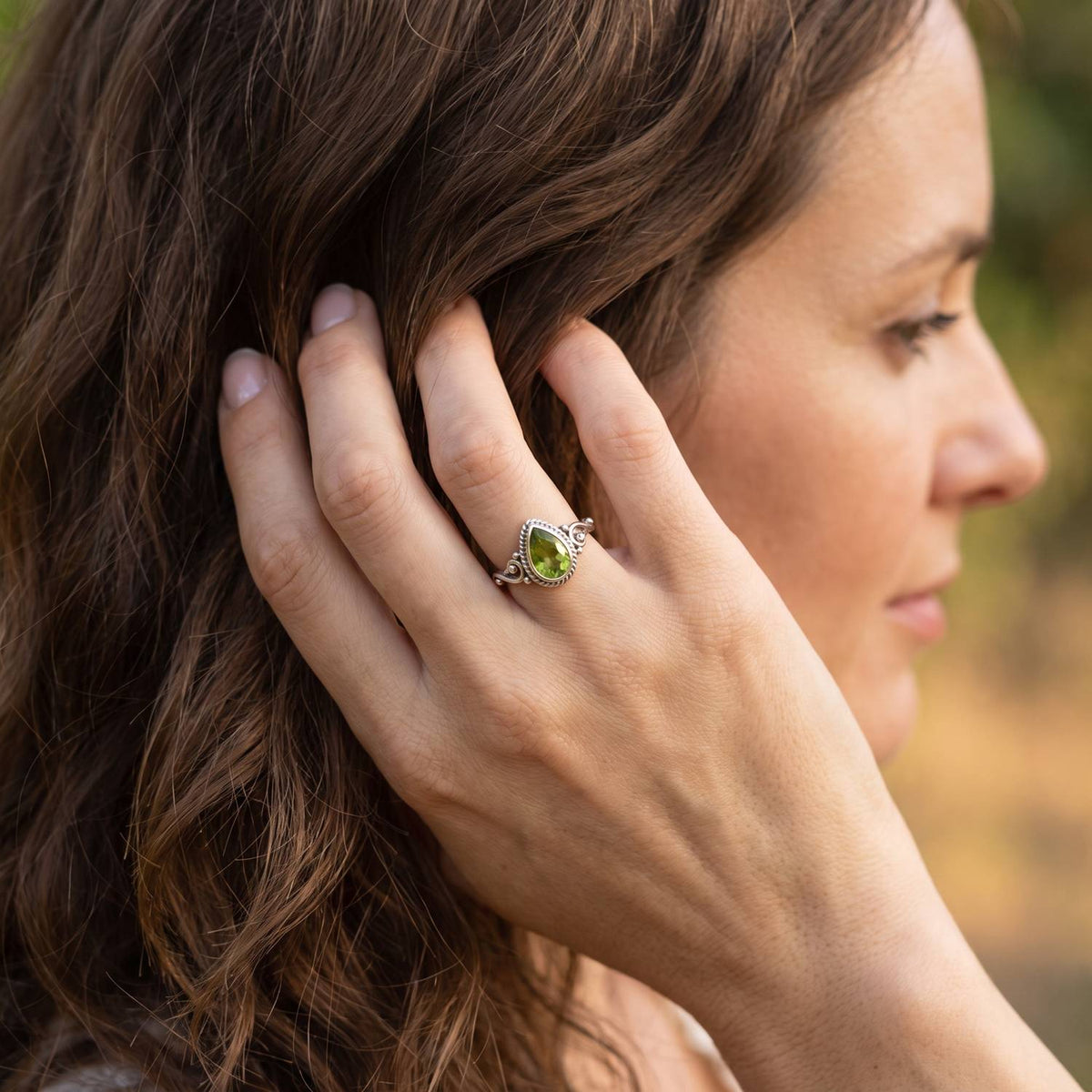 Frau trägt Silberring mit Peridot an der Hand am Haar