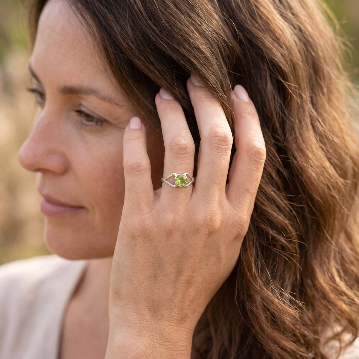 Frau trägt Silberring mit Peridot an der Hand am Haar