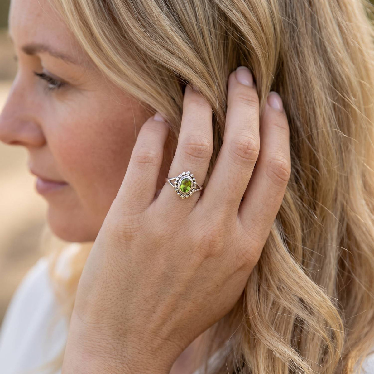 Frau trägt Silberring mit Peridot an der Hand am Haar